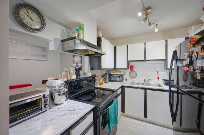Kitchen featuring a sink, white cabinetry, light tile patterned floors, a toaster, and black appliances | Image 9