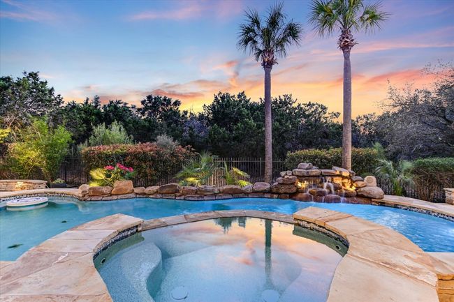 resort style pool with cascading water feature, spa, in pool table, mosaic tile design of turtles in the pool | Image 37