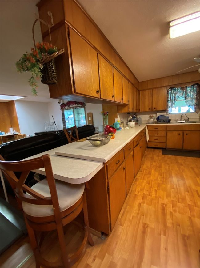 Kitchen featuring light countertops, light wood-style floors, brown cabinets, and a sink | Image 10