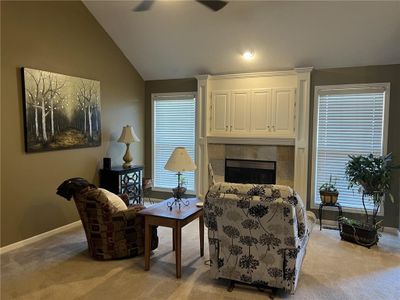 Carpeted living room with ceiling fan, lofted ceiling, and a tile fireplace | Image 2