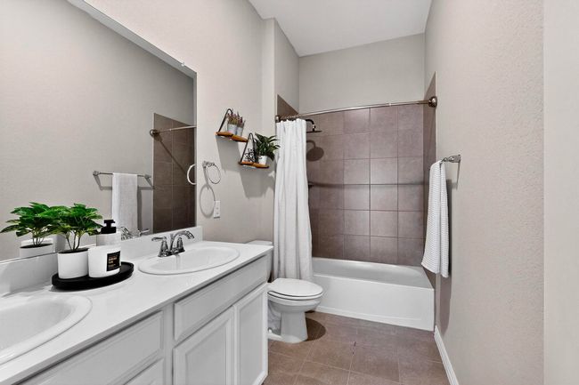 Full bath featuring shower / bath combo with shower curtain, double vanity, and light tile patterned floors | Image 31