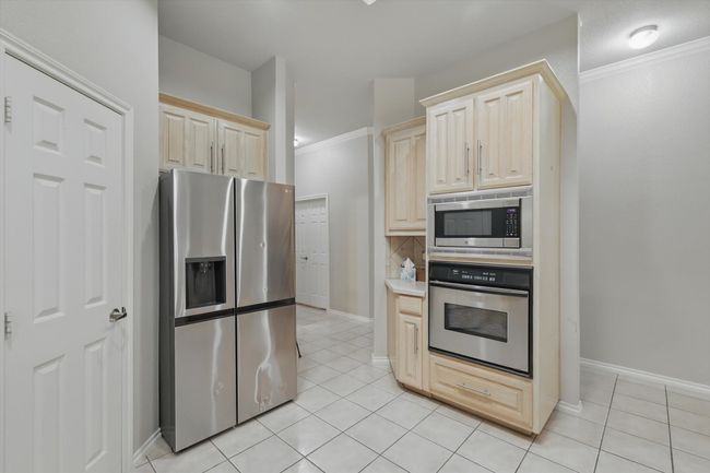Kitchen featuring light tile patterned floors, light brown cabinetry, and stainless steel appliances | Image 13