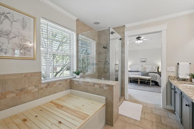 Ensuite bathroom featuring a stall shower, vanity, ceiling fan, ornamental molding, and tile patterned flooring | Image 20