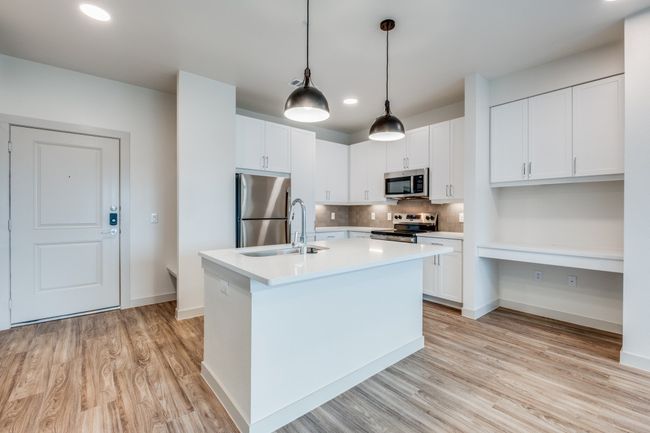 Kitchen featuring tasteful backsplash, a center island with sink, light countertops, light wood-style flooring, and stainless steel appliances | Image 11