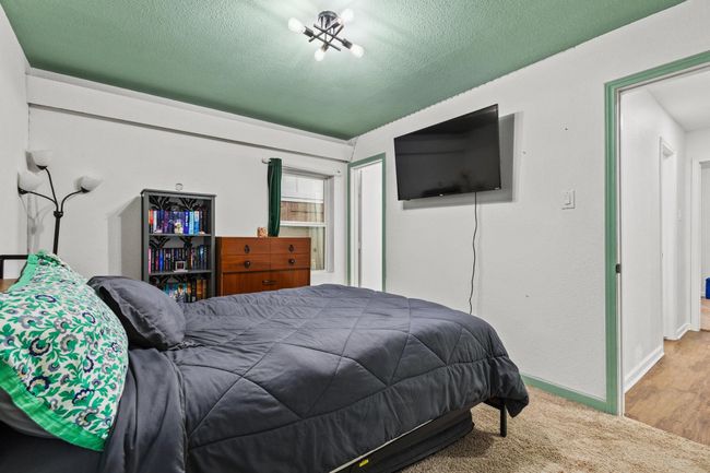 Bedroom with a textured ceiling, baseboards, a closet, and wood finished floors | Image 19