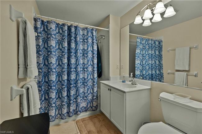 Bathroom with a shower with curtain, vanity, toilet, and tile patterned flooring | Image 15
