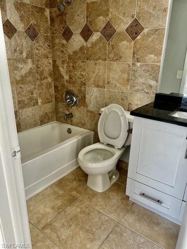 Full bath featuring toilet, tub / shower combination, vanity, and tile patterned flooring | Image 15