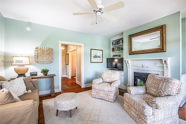 Living room with built in shelves, hardwood / wood-style floors, and ceiling fan | Image 12