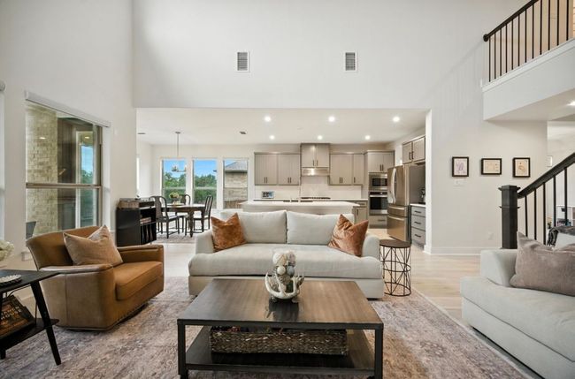 Living room with a high ceiling, light wood finished floors, stairway, and recessed lighting | Image 7