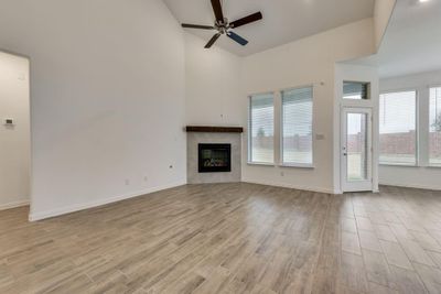 Unfurnished living room with ceiling fan, light wood-type flooring, and a high ceiling | Image 2