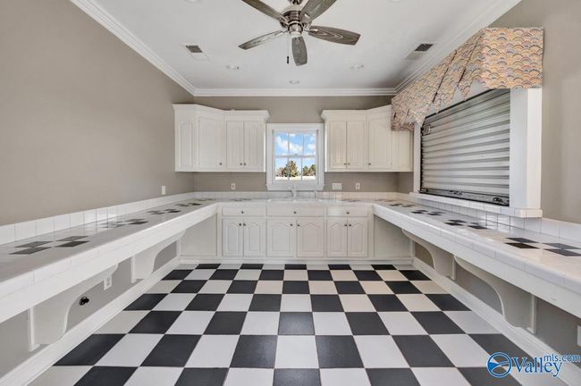 Rollup serving window, Tile counters, recessed lighting, ceiling fan, crown molding, wood cabinetry, sink | Image 46