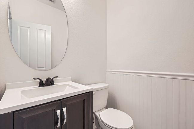 Half bathroom featuring toilet, vanity, and a wainscoted wall | Image 14