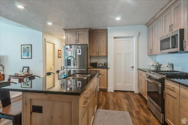 Kitchen with appliances with stainless steel finishes, a sink, dark wood finished floors, a kitchen breakfast bar, and recessed lighting | Image 9