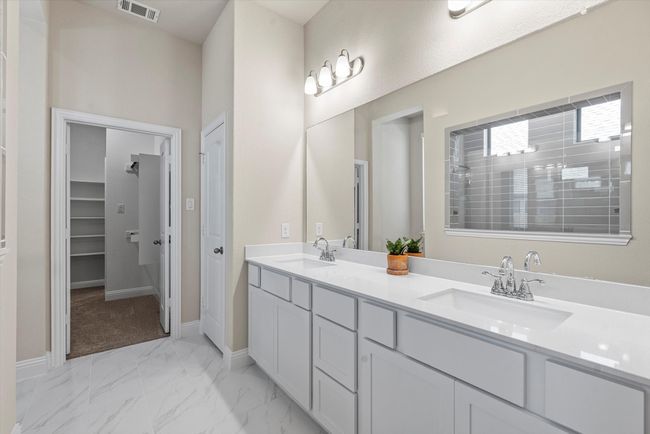 Full bathroom with double vanity, baseboards, and marble look tile flooring. | Image 13