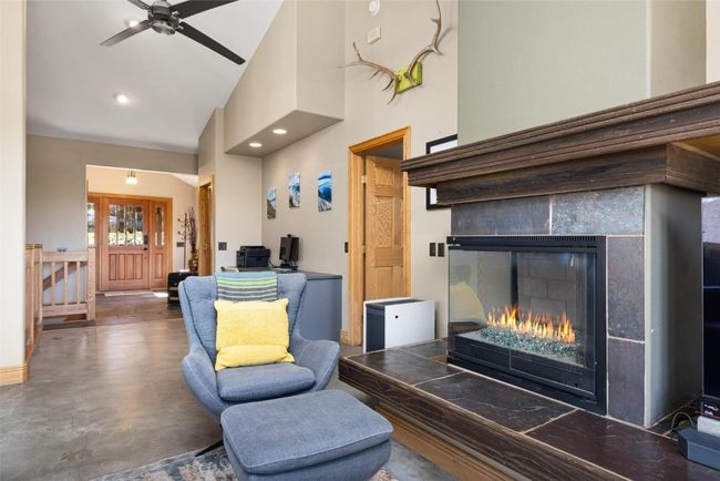 Living area with high vaulted ceiling, concrete flooring, a tiled fireplace, and a ceiling fan | Image 6
