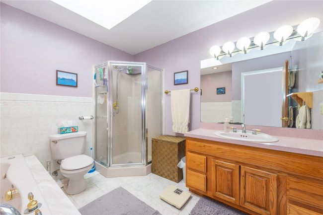 Bathroom featuring a skylight, tile walls, a shower stall, and toilet | Image 28