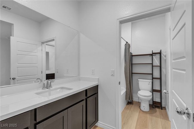 Full bath featuring vanity, wood finished floors, toilet, shower / bath combo with shower curtain, and baseboards | Image 14