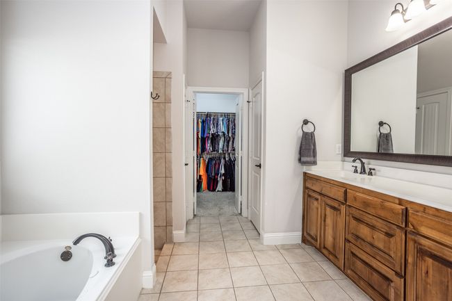 Bathroom with vanity, a bath, tile patterned floors, a walk in closet, and a shower | Image 24