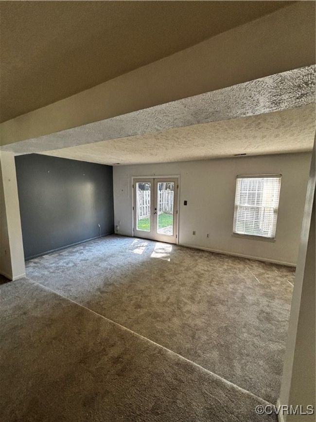 Carpeted room featuring french doors and a textured ceiling | Image 8