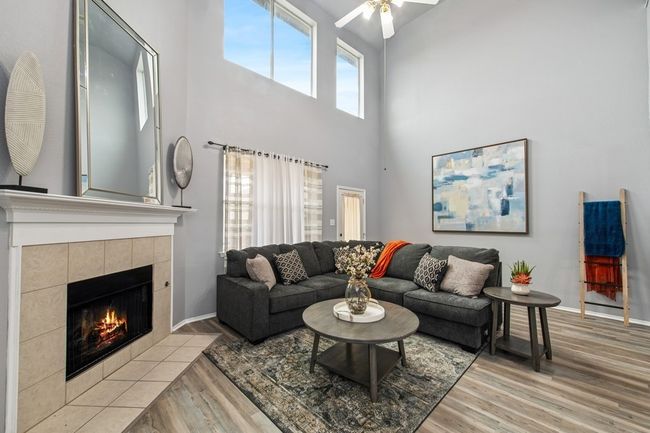 Living room featuring light wood-style flooring, a ceiling fan, baseboards, and a fireplace | Image 20