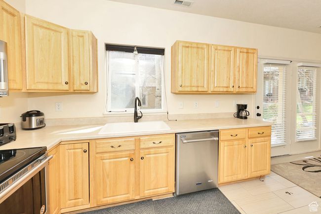 Kitchen featuring light countertops, a sink, light brown cabinets, and stainless steel appliances | Image 5