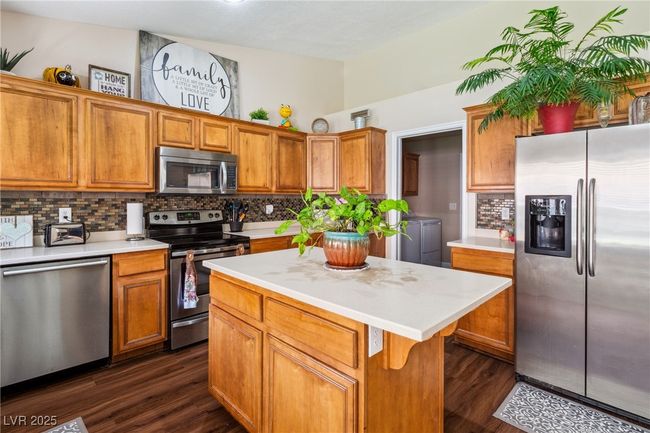 Kitchen featuring appliances with stainless steel finishes, separate washer and dryer, dark wood-style flooring, tasteful backsplash, and light countertops | Image 15