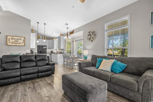 Living room featuring high vaulted ceiling, a ceiling fan, light wood-style flooring, baseboards, and visible vents | Image 19