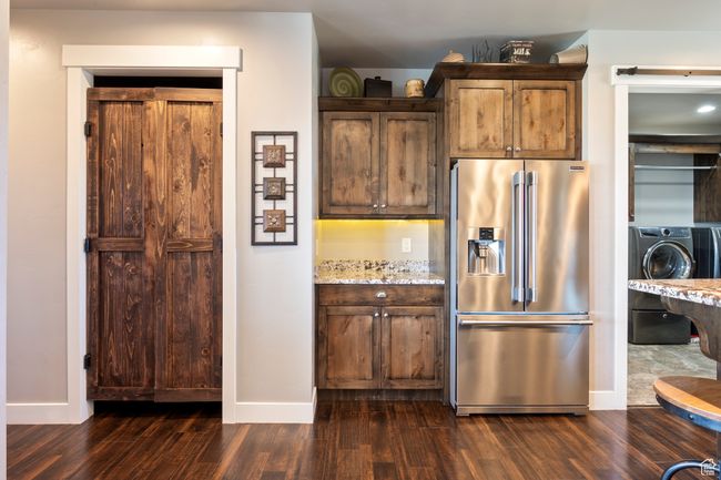 Kitchen with washer / clothes dryer, baseboards, high quality fridge, light stone countertops, and dark wood-type flooring | Image 14