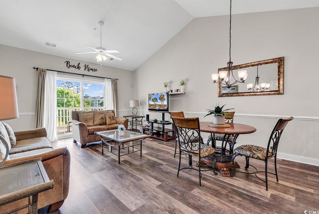 Dining space featuring high vaulted ceiling, dark wood-style floors, ceiling fan with notable chandelier, and visible vents | Image 7