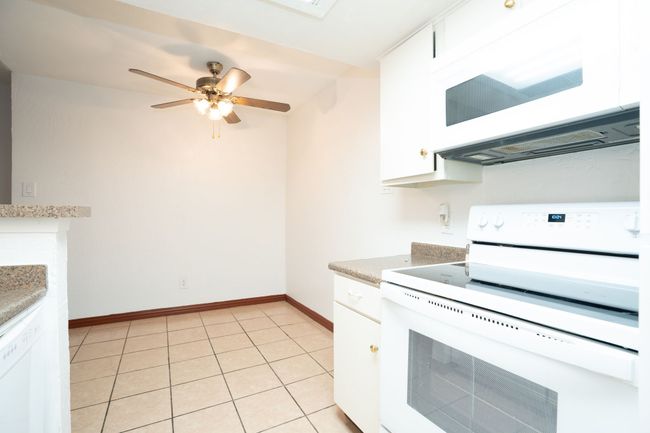 Kitchen with white cabinets, light countertops, white appliances, baseboards, and ceiling fan | Image 8