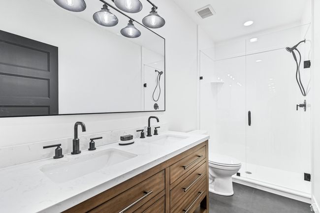 Bathroom featuring a shower stall, double vanity, visible vents, and a sink | Image 31