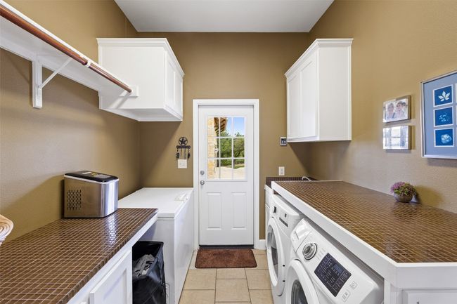 Washroom with cabinet space, light tile patterned floors, and washer and clothes dryer | Image 39
