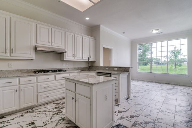 Kitchen featuring light marble finish flooring, a sink, recessed lighting, under cabinet range hood, and white cabinetry | Image 8