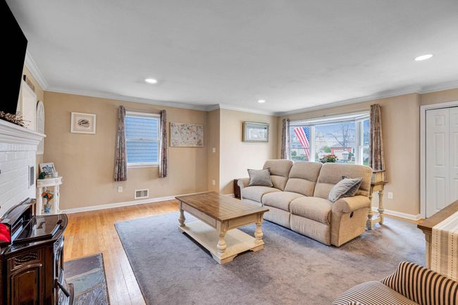 Living area featuring baseboards, crown molding, wood finished floors, and visible vents | Image 29