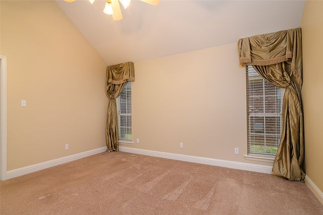 Unfurnished room with carpet floors, a ceiling fan, baseboards, and lofted ceiling | Image 9
