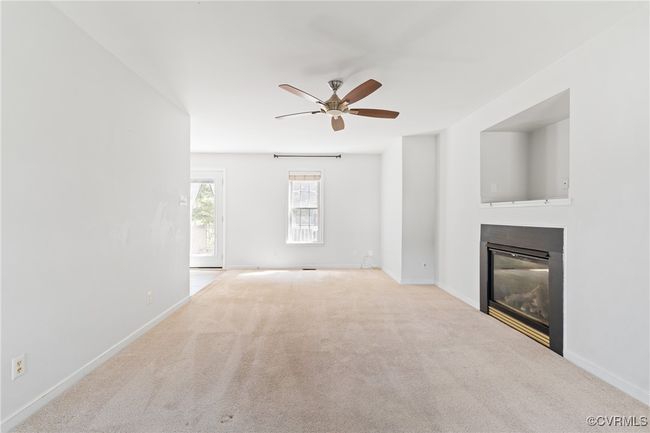 Unfurnished living room featuring a glass covered fireplace, ceiling fan, and carpet floors | Image 13