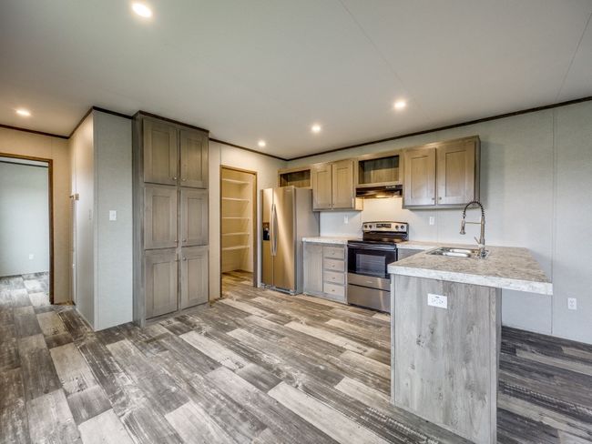 Kitchen featuring light countertops, a sink, appliances with stainless steel finishes, light wood-type flooring, and under cabinet range hood | Image 7