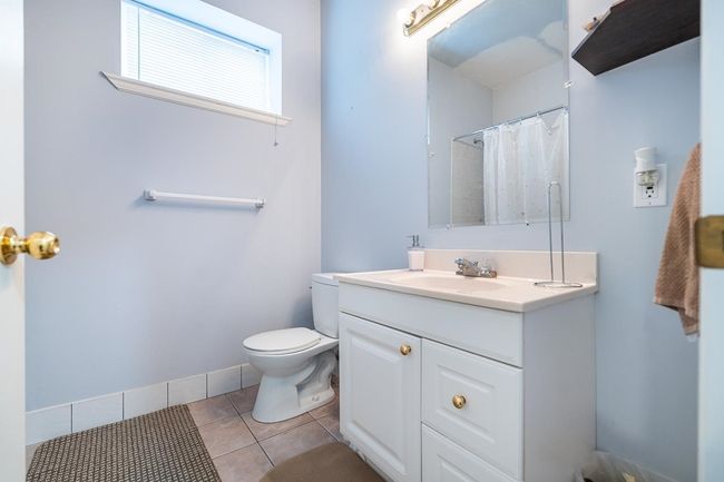 Full bathroom with baseboards, toilet, vanity, a shower with curtain, and tile patterned flooring | Image 35