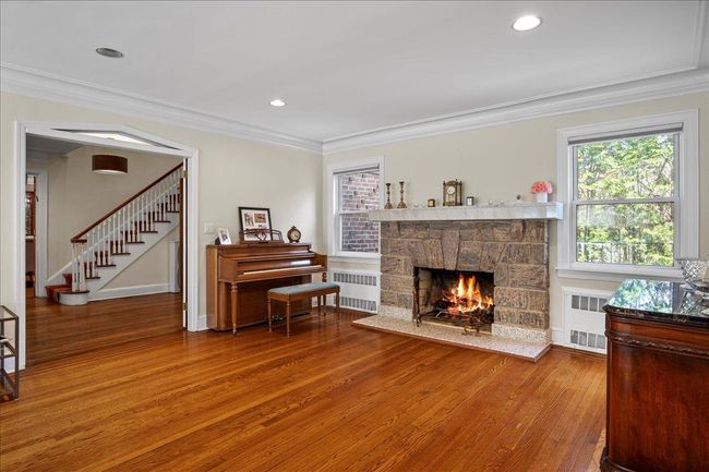 Living area featuring a stone fireplace, ornamental molding, and wood finished floors | Image 9