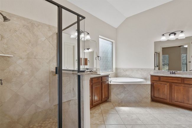 Bathroom with a shower stall, vaulted ceiling, a garden tub, two vanities, and tile patterned floors | Image 29