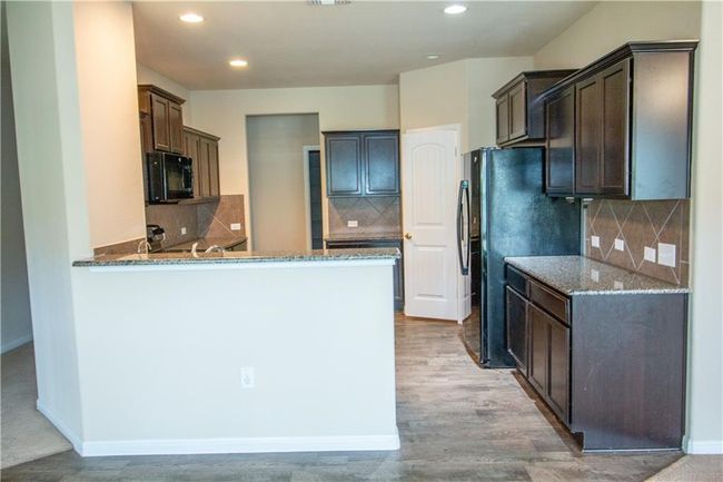 Kitchen with stone countertops, a peninsula, black appliances, tasteful backsplash, and recessed lighting | Image 14