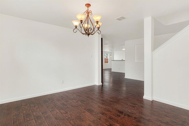 Unfurnished room featuring a chandelier, dark wood-style floors, and baseboards | Image 9