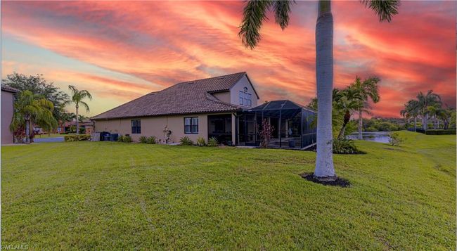 Back of property featuring a lanai, stucco siding, a yard, and a water view | Image 30