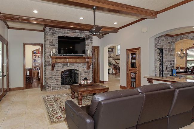 Family room highlights include wood ceiling beams, stone fireplace, TV mounting and attractive wood mantle. | Image 11