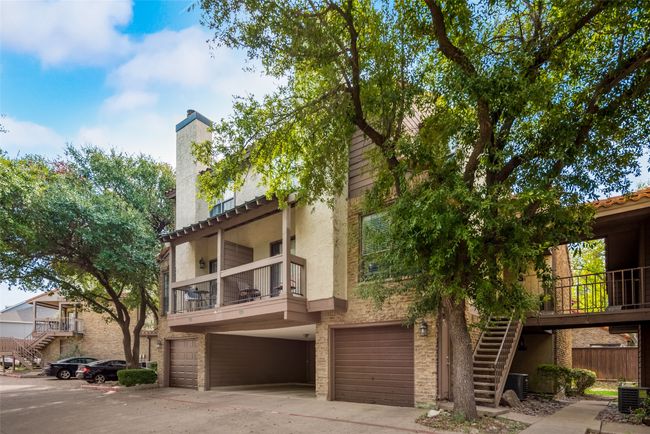 View of front of home featuring stairs, an attached garage, a chimney, stucco siding, and brick siding | Image 18