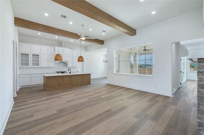 Kitchen with a spacious island, hardwood / wood-style flooring, beam ceiling, white cabinets, and tasteful backsplash | Image 6