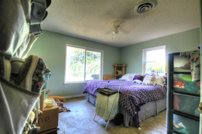Carpeted bedroom featuring multiple windows, a textured ceiling, baseboards, and ceiling fan | Image 10