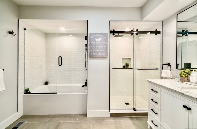 The primary bathroom is made for relaxation with its separate shower and tub, porcelain tile, and charming vanity. | Image 15