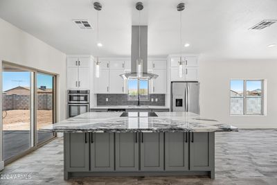 Large island with grey cabinets and granite countertops. | Image 2