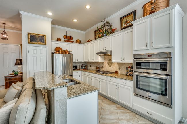Kitchen featuring stainless steel appliances, under cabinet range hood, ornamental molding, white cabinetry, and decorative backsplash | Image 11